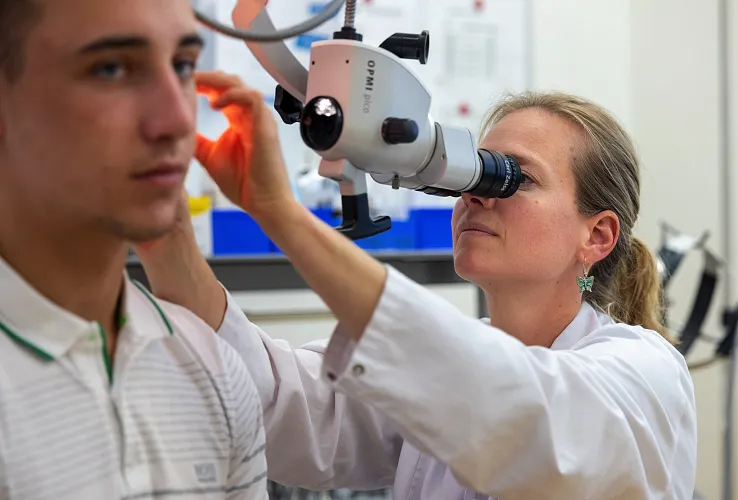 Ein Arzt untersucht das Ohr eines jugendlichen Patienten mit einem medizinischen Instrument in einer klinischen Umgebung.