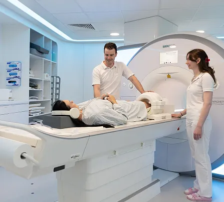 Eine Patientin liegt in einem modernen MRT-Gerät, betreut von zwei medizinischen Fachkräften in einem hellen, sauberen Untersuchungsraum.