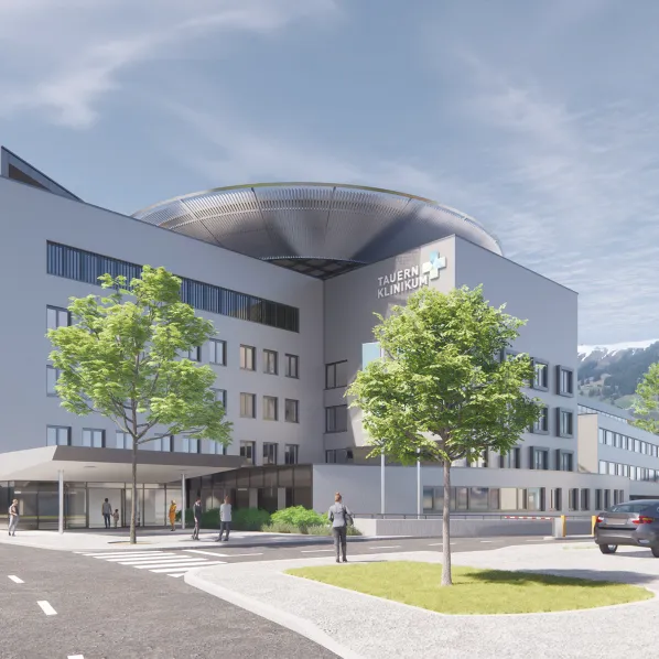 Modernes Krankenhausgebäude mit weißen Fassaden, großen Fenstern und einem runden Dach. Im Vordergrund Bäume, Autos und Menschen. Berge im Hintergrund.